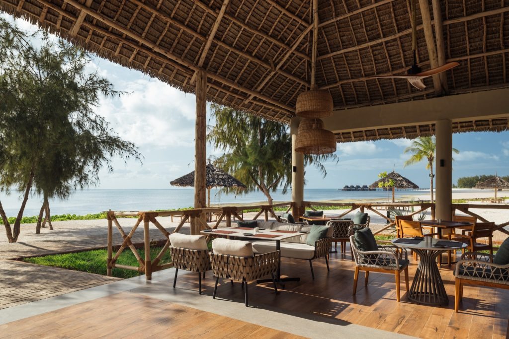 Offene Terrasse des Restaurants Breeze im JAZ Elite Aurora mit Holzmöbeln, Schilfdach und Blick auf Strand und Meer