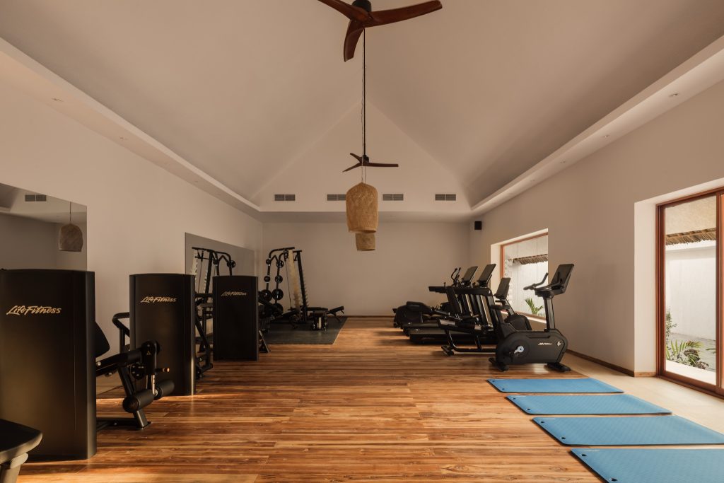 Moderner Fitnessraum im JAZ Elite Aurora mit Holzfußboden, Laufbändern, Kraftstationen und großen Fenstern
