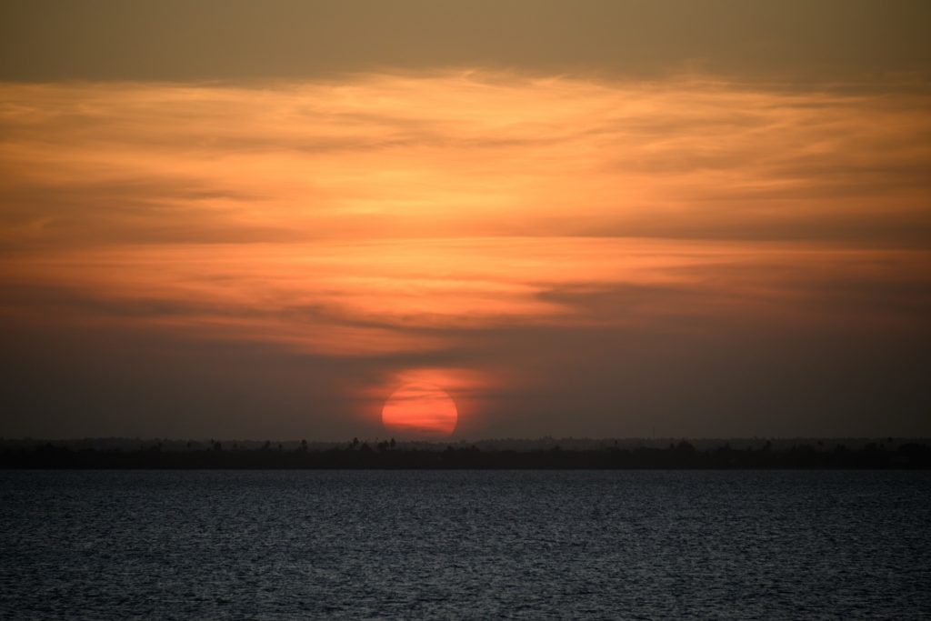 Sonnenuntergang über Wasser am Strand des JAZ Elite Aurora mit schmaler Landlinie und Bäumen am Horizont