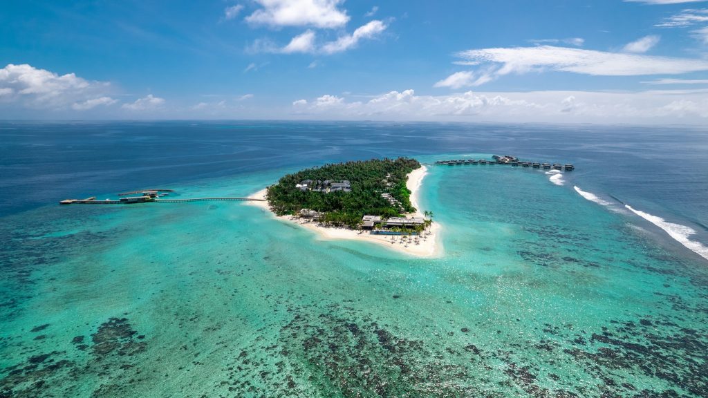Luftaufnahme der Insel Alila Kothaifaru Maldives mit grüner Vegetation, Holzbungalows auf Stelzen und türkisfarbenem Wasser