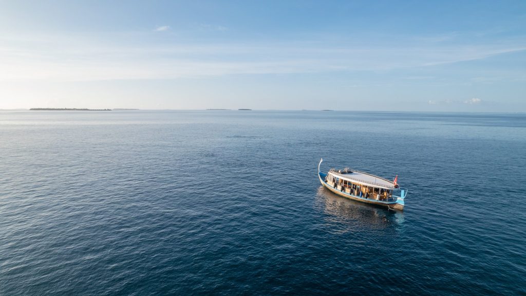 Traditionelles Holzboot mit blauen Farbtönen auf klarem Wasser im Wassersportzentrum Alila Kothaifaru Maldives