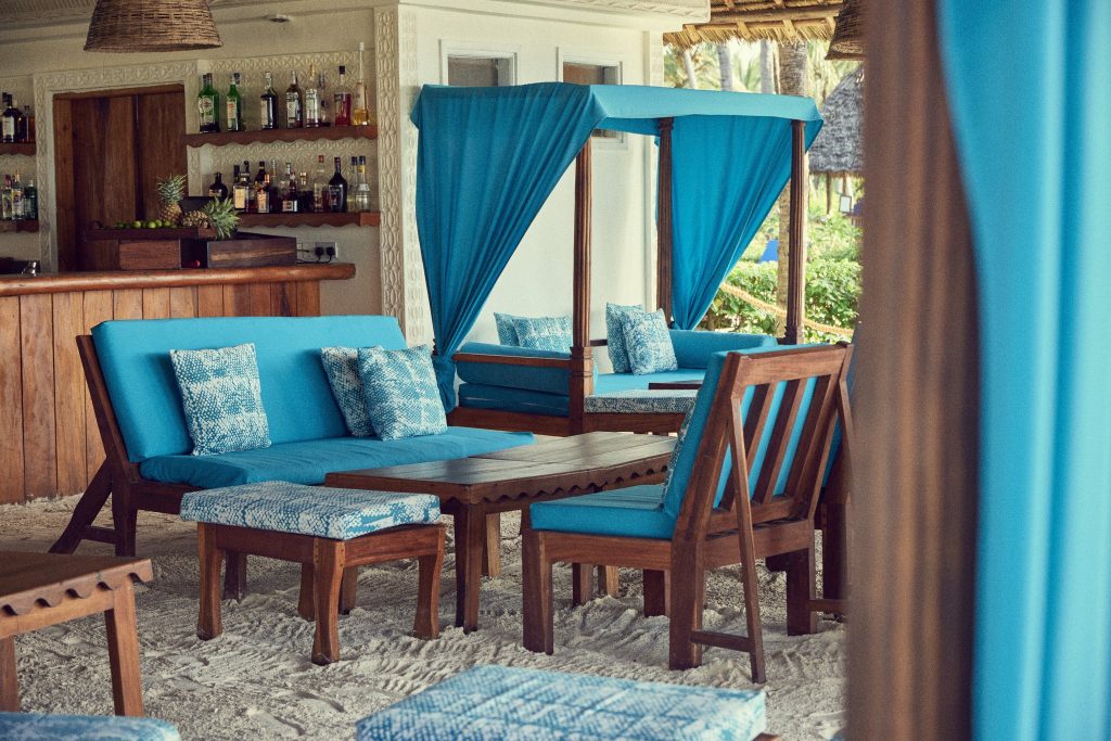 Gemütlicher Barbereich im Breezes Beach Club And Spa mit Holzbar, blauen Sitzpolstern und hellem Sandboden