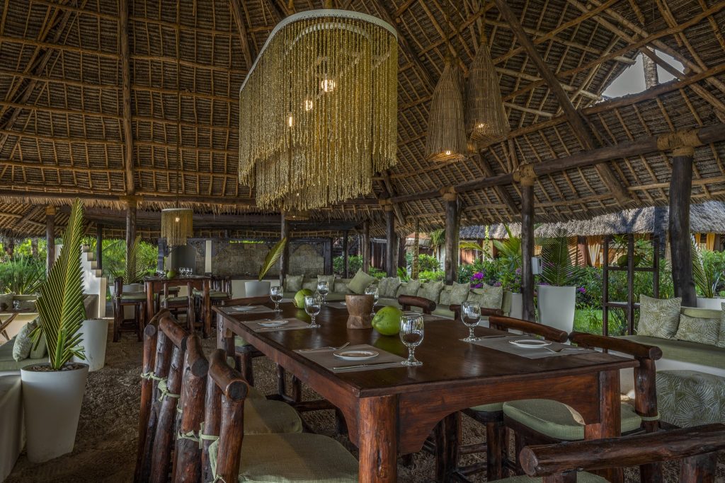 Offenes Restaurant Breakers Grill mit Holztischen, Bambusdecke und großer grüner Landschaft in Sansibar