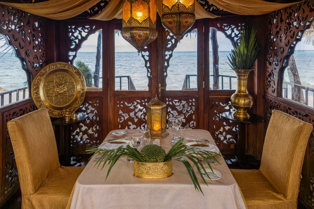 Essbereich im Restaurant Tides im Breezes Beach Club And Spa mit geschnitzten Holzwänden und goldfarbenen Stühlen am Meer