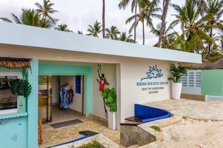 Tauchzentrum Breezes Beach Club And Spa mit flachem Dach, weiß-türkiser Fassade und aufgehängten Tauchanzügen