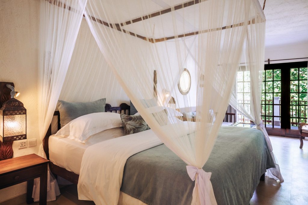 Deluxe Room im Breezes Beach Club And Spa mit Himmelbett und Moskitonetz, offenen Fenstern und dunklem Holz