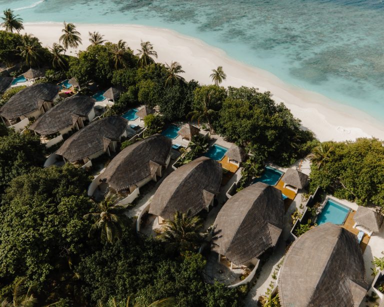 Reihe von Bungalows mit privaten Pools an weißem Sandstrand und türkisfarbenem Meer auf den