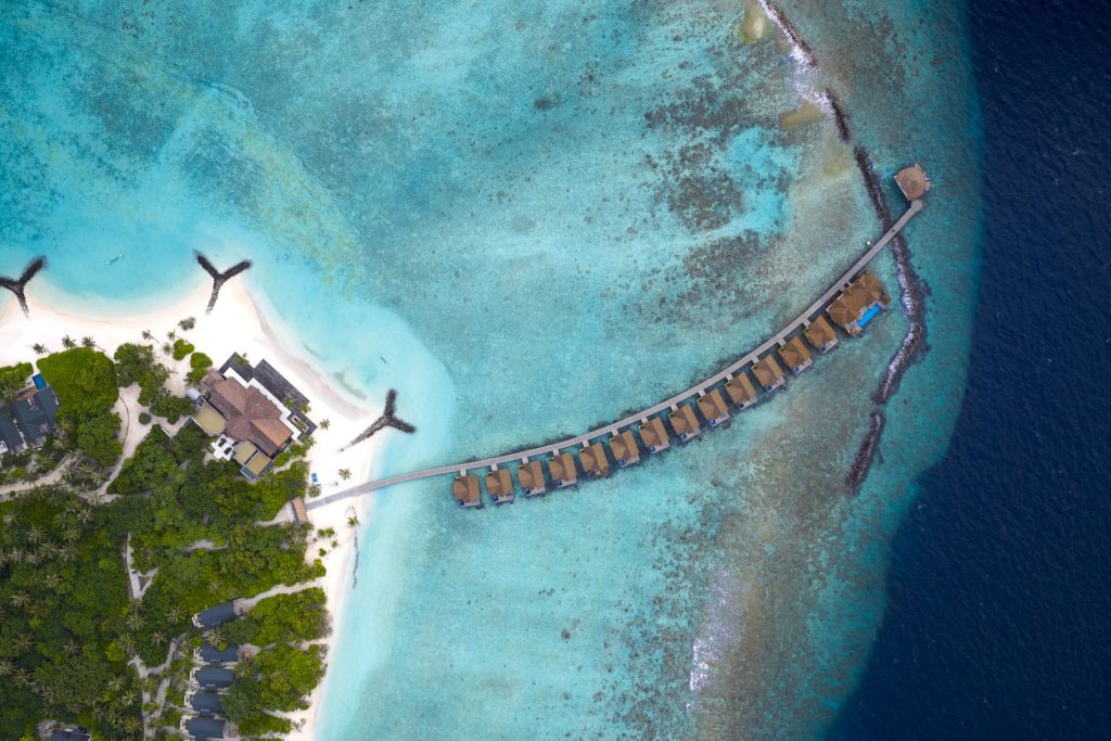Luftaufnahme des Furaveri Maldives Resorts mit Wasserbungalows, weißem Sandstrand und grüner Inselvegetation unter Tageslicht