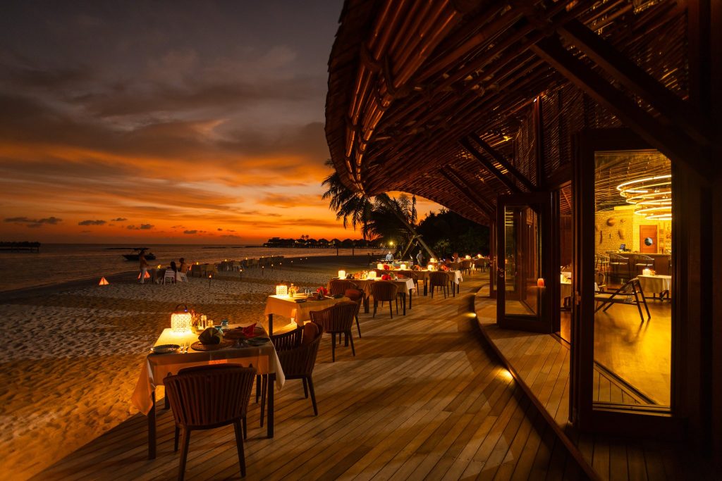 Strandrestaurant Restaurant Aqua bei Furaveri Maldives mit gedeckten Tischen und Kerzenlicht in der Dämmerung