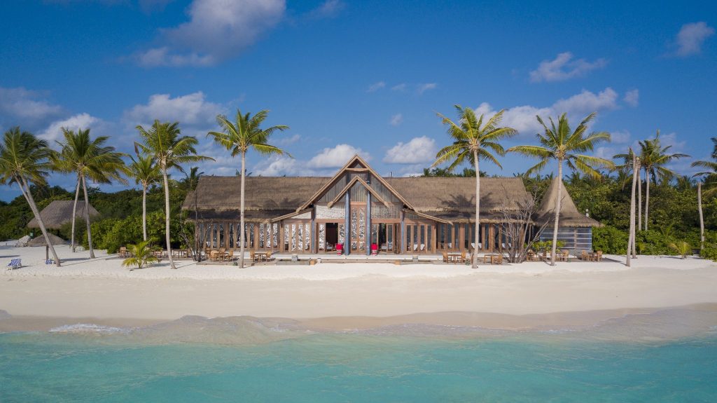 Restaurant Raiyvilla mit Strohdach, Holztischen und Stühlen unter Palmen am weißen Sandstrand auf den