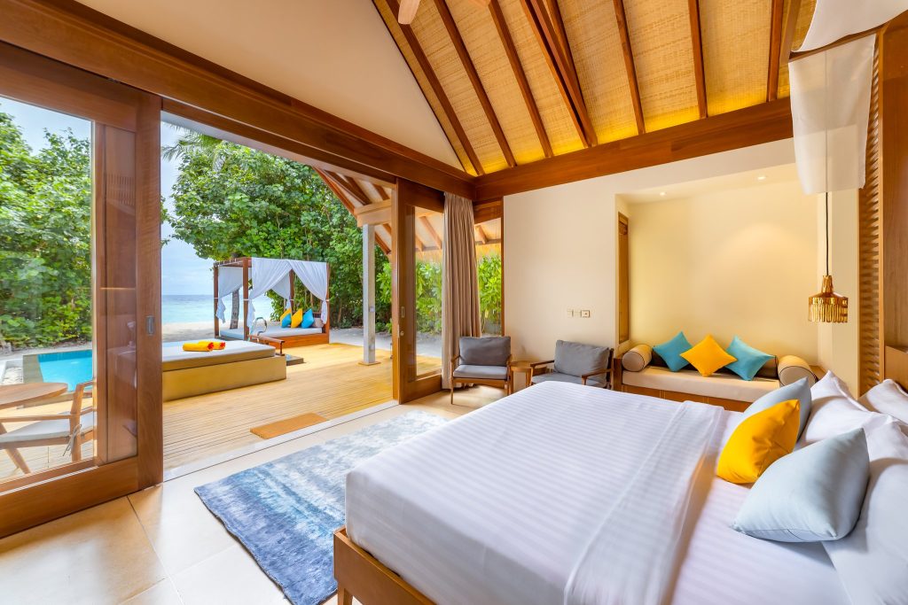 Zimmer der Beach Pool Villa mit großem Bett, Sitzecke, Holz- und Glaselementen und Terrasse mit kleinem Pool