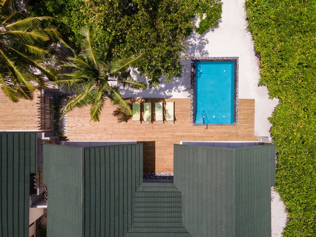 Vogelperspektive auf rechteckigen Pool mit Holzterrasse, Liegestühlen und Palmen im Furaveri Maldives Two Bedroom Private.