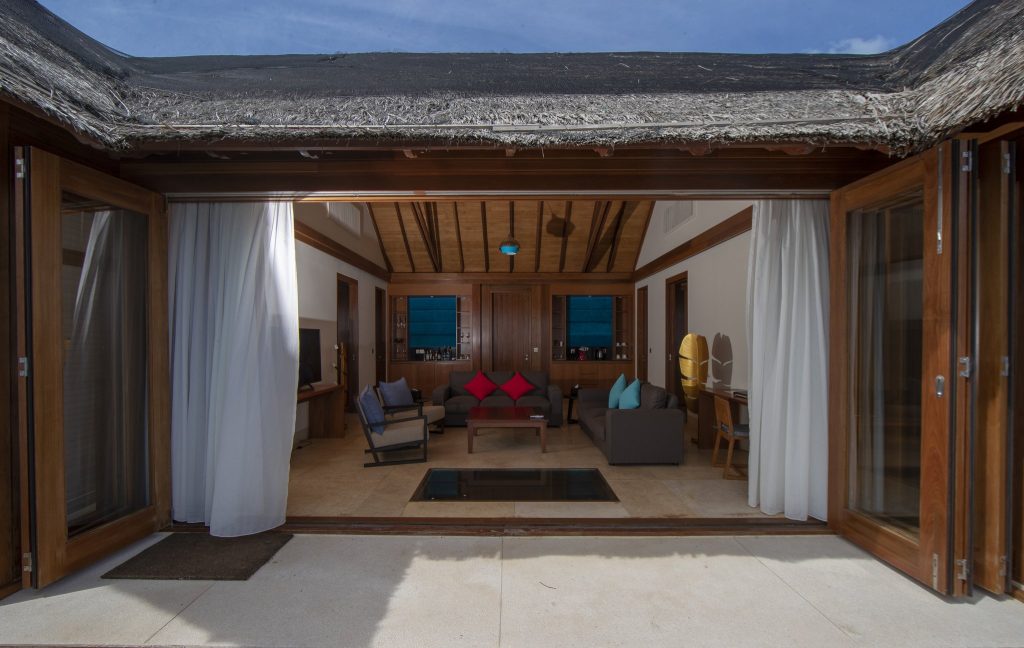 Offener Wohnbereich der Two Bedroom Private Reef Residence mit Holzkonstruktion, großen Glastüren und beigen Fliesenböden