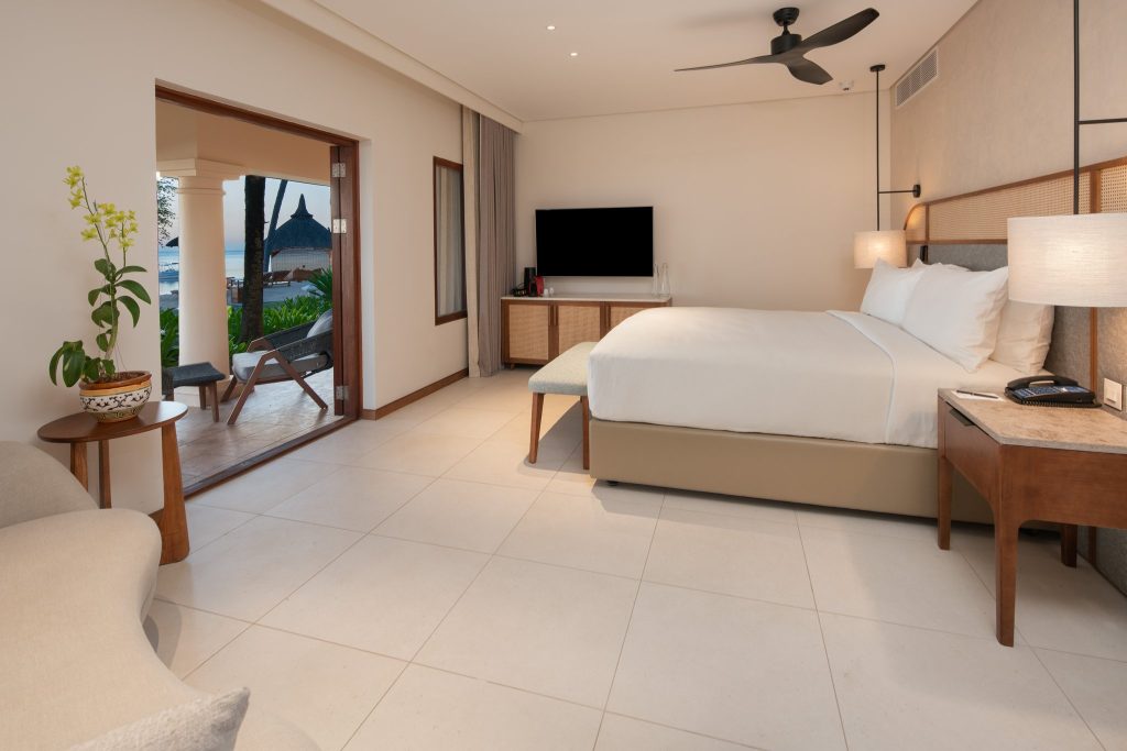 Modernes Hotelzimmer mit großem Bett, Holzmöbeln, Balkon und Meerblick im Hilton Mauritius Resort & Spa Honeymoon Suite