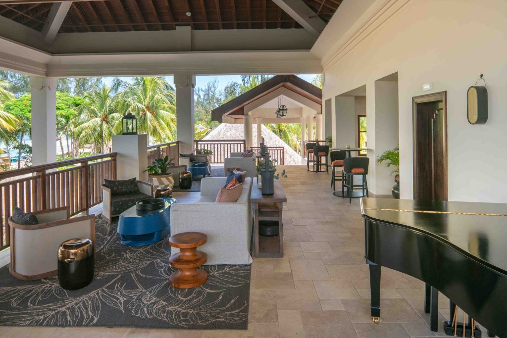 Hotelterrasse der Bar im Hilton Mauritius Resort & Spa mit Sofas, Sesseln, Holztischen und Blick auf tropische Vegetation