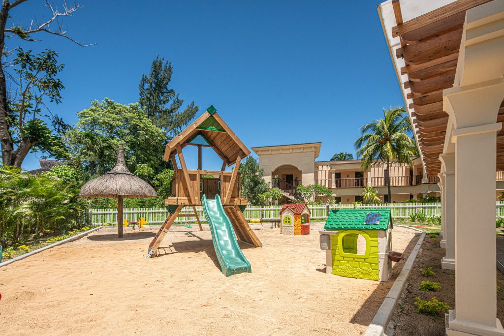Spielplatz mit Holzkonstruktion, grüner Rutsche, Sandboden und Palmen im Hilton Mauritius Resort & Spa