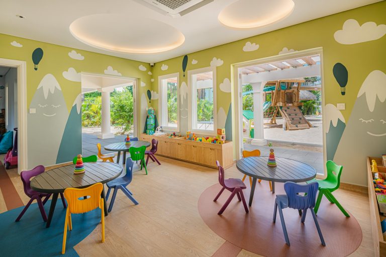 Kinderbereich mit ovalen Holztischen, bunten Stühlen und kindgerechten Wandmalereien im Hilton Mauritius Resort & Spa