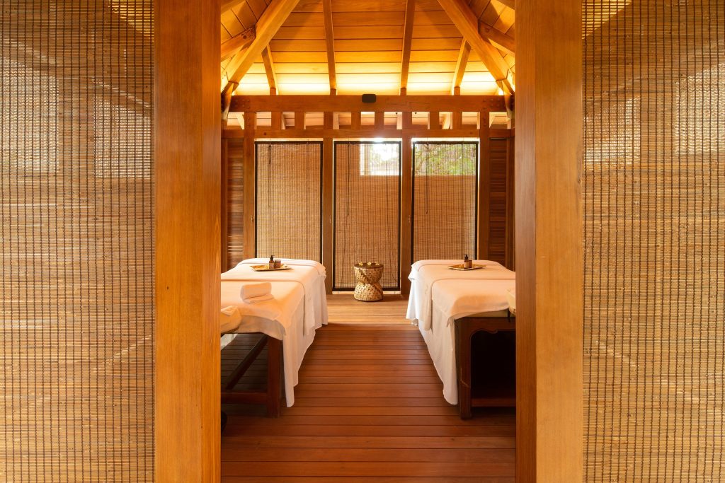 Spa-Raum im Hilton Mauritius Resort & Spa mit zwei Massagetischen, Holz- und Bambuselementen sowie warmem Licht