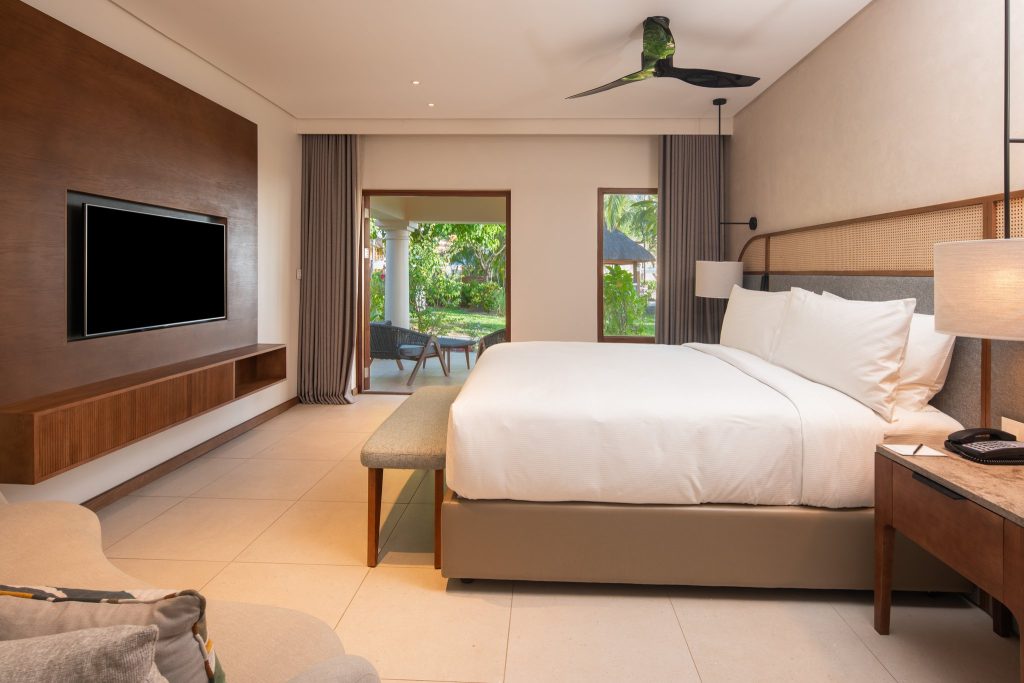 Geräumiges Beach Front Family Suite Zimmer mit großem weißen Bett, Flachbildfernseher, Holzpaneel und Terrasse