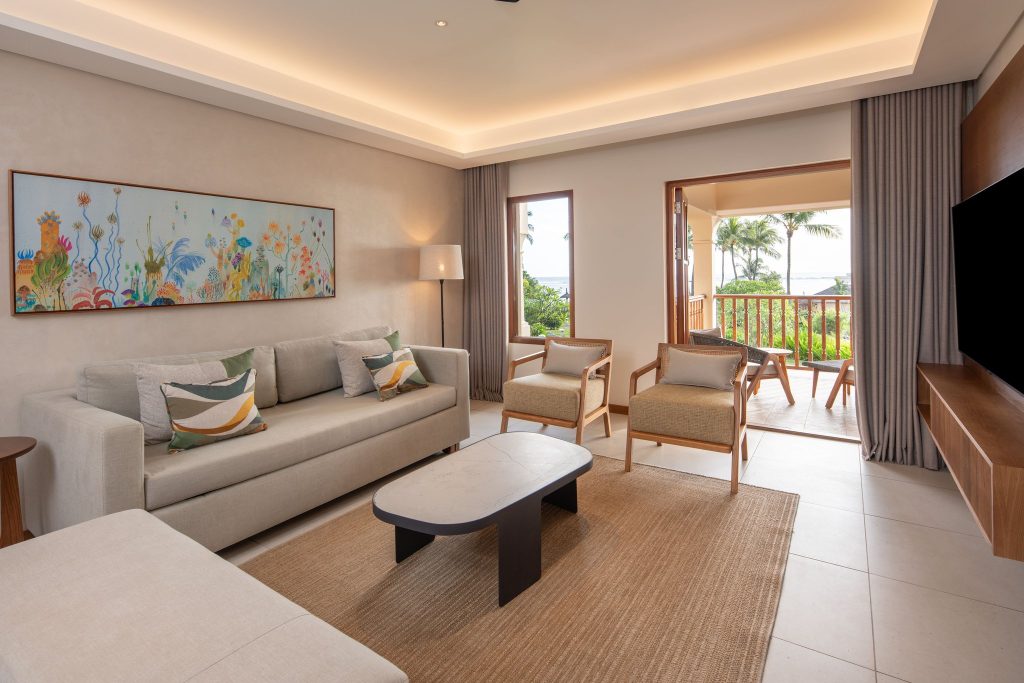 King Family Suite mit Wohnzimmer, großem Sofa, Holzsesseln, Couchtisch und Balkon mit Naturblick