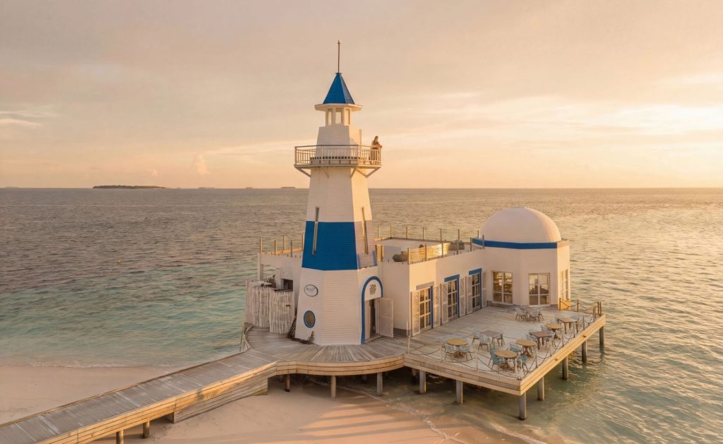 Restaurant lighthouse am Meer mit hölzernem Steg, weißen Tischen und Stühlen, blau-weißem Gebäude bei Dämmerung