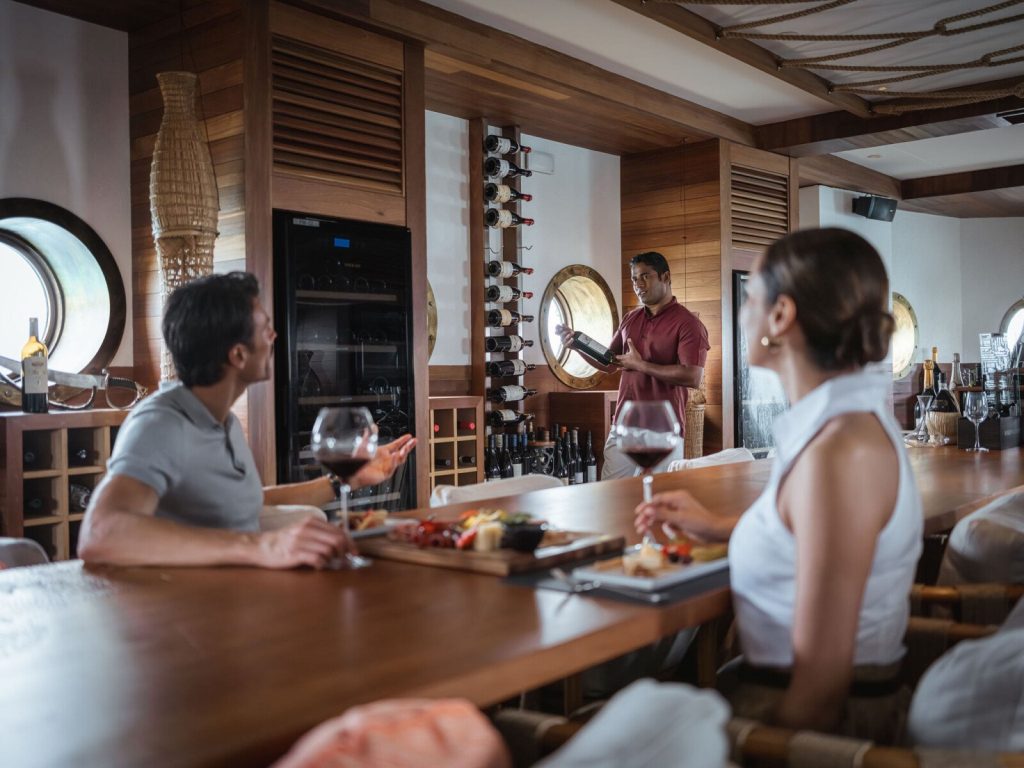Innenraum der Weinbar im InterContinental Maldives Maamunagau Resort mit Holzregal und Bullaugenfenstern