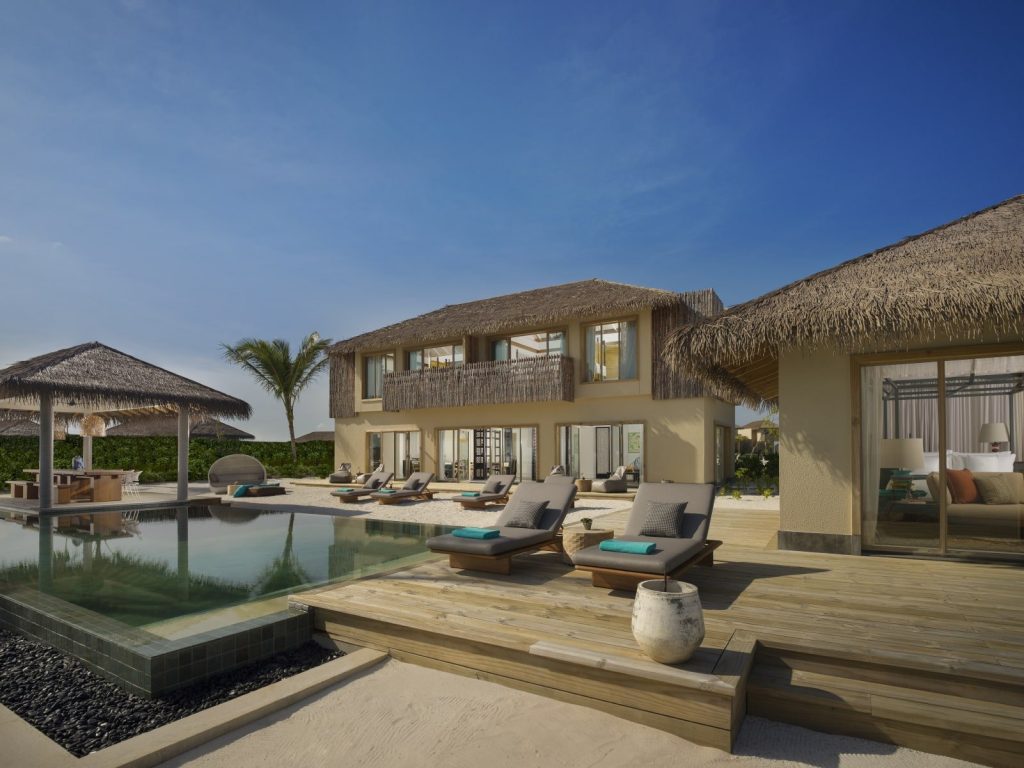 Infinity-Pool mit hölzernen Liegeflächen, grauen Kissen und türkisfarbenen Handtüchern im InterContinental Maldives.