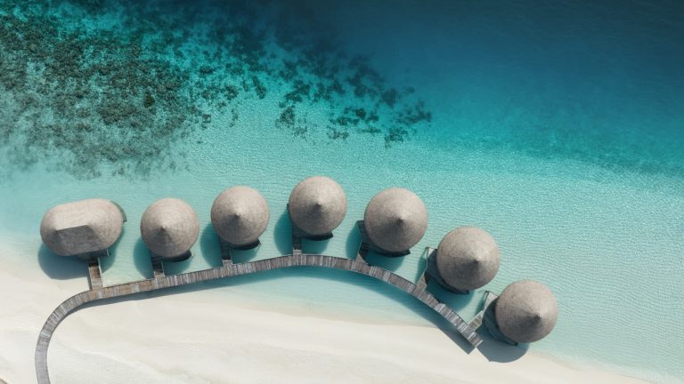 Luftaufnahme runder Hütten mit Strohdächern auf Steg über türkisem Wasser im InterContinental Maldives Maamunagau Resort