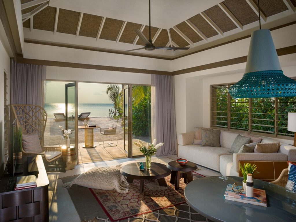 Wohnraum der 2 Bedroom Family Beach Pool Villa mit Holzmöbeln, großer Couch und Meerblick durch