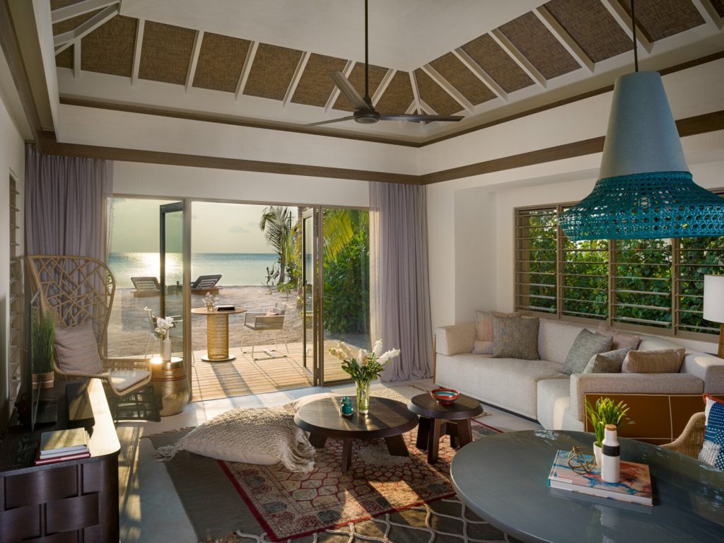 Wohnbereich der 2 Bedroom Family Beach Pool Villa mit Holztisch, Sofagarnitur und Meerblick auf den