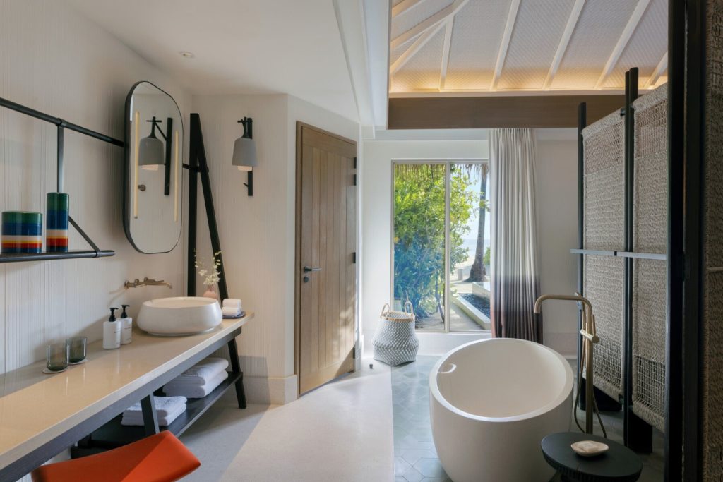 Modernes Badezimmer mit runder freistehender Badewanne, Waschtisch mit ovalem Spiegel, Holz- und Steinmaterialien.
