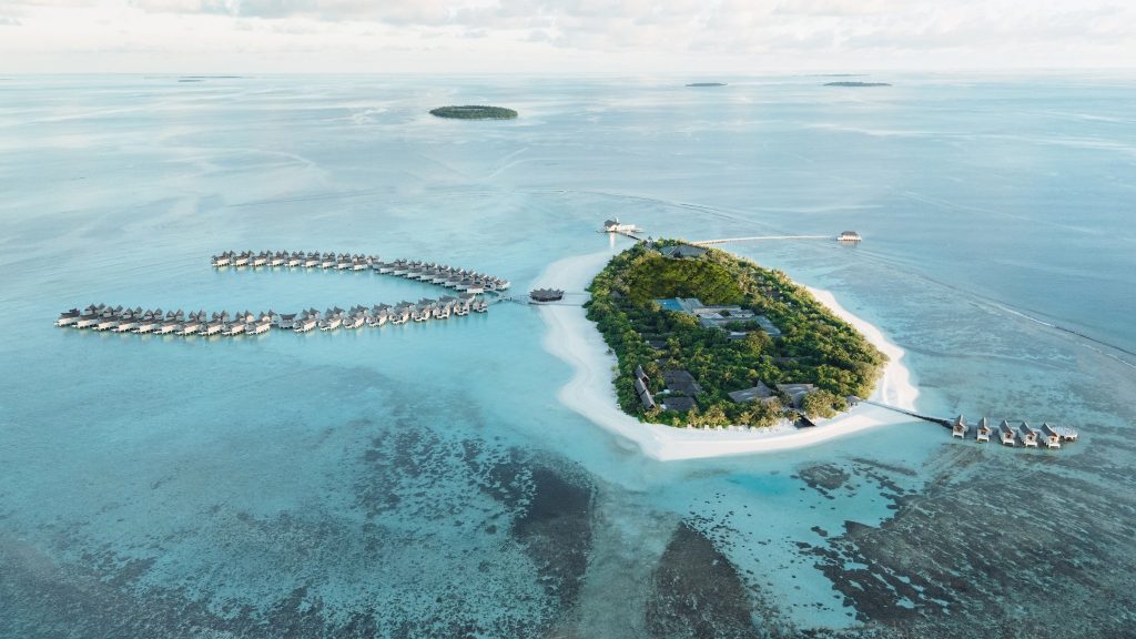 Luftaufnahme der tropischen Insel des Kuredhivaru Resort and Spa Maldives mit über Wasser gebauten Bungalows und umgebendem.
