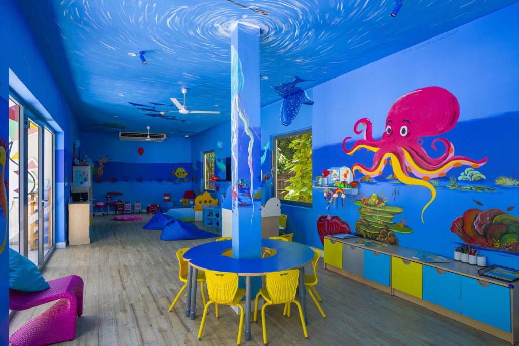 Kinderzimmer im Kuredhivaru Resort and Spa Maldives mit blau gestrichenen Wänden, Meerestiere-Illustrationen und bunten.