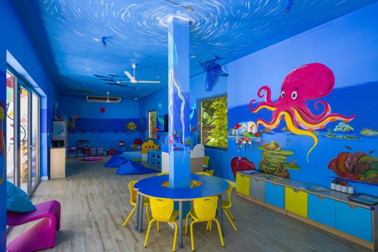 Kinderzimmer im Kuredhivaru Resort and Spa Maldives mit blau gestrichenen Wänden, Meerestiere-Illustrationen und bunten.