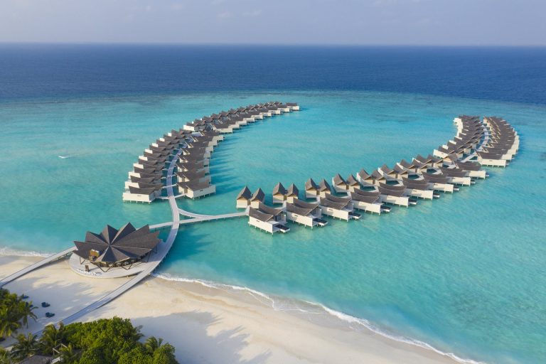 Luftaufnahme des Kuredhivaru Resort and Spa Maldives mit auf Stelzen gebauten Bungalows über türkisfarbenem Wasser