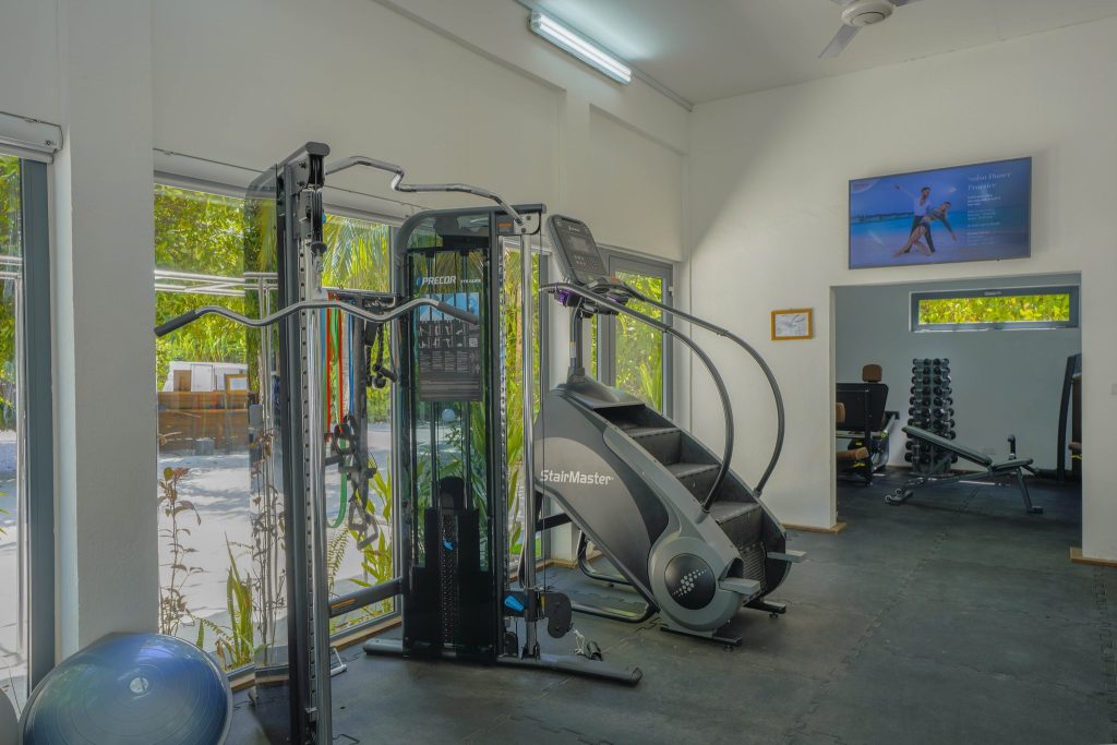 Fitnessraum im Kuredhivaru Resort and Spa Maldives mit Kraftgerät, StairMaster und großen Panoramafenstern