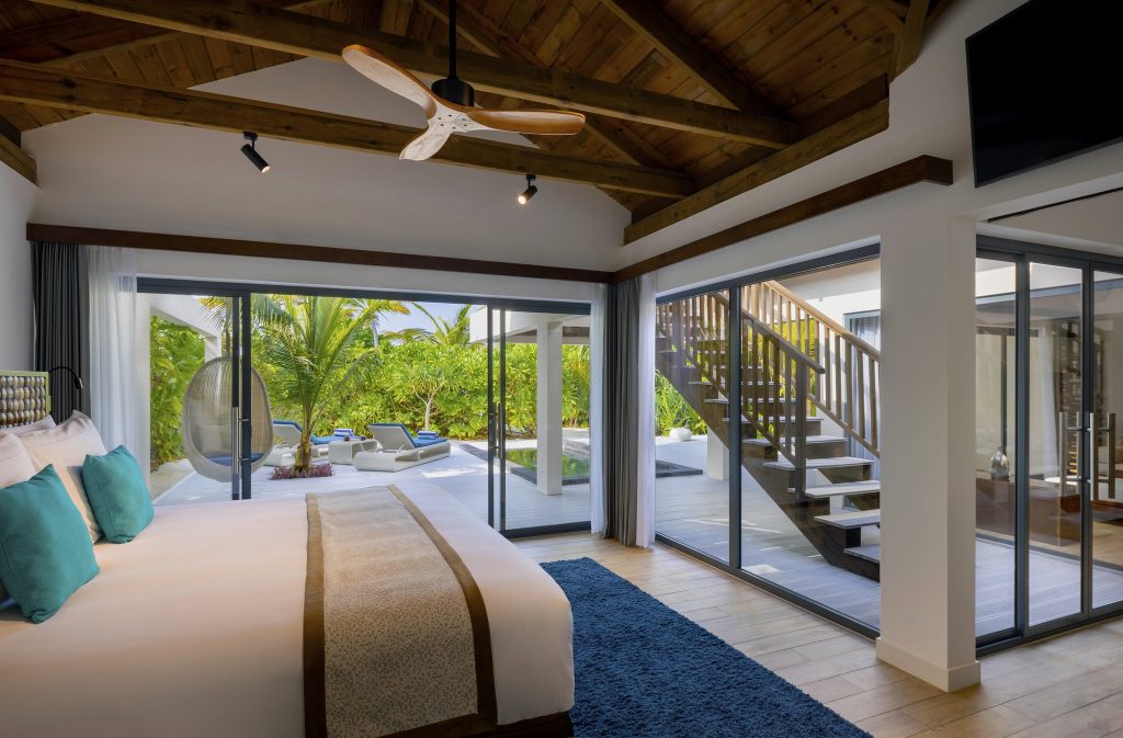 Modern eingerichtetes Deluxe Beach Pool Villa Zimmer mit Glasfronten, Blick auf Terrasse, Pool und Grün
