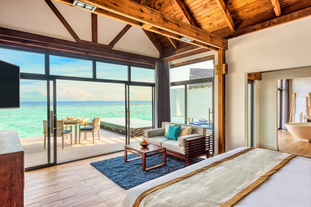 Zimmer der Overwater Pool Villa im Kuredhivaru Resort mit Holzbalken, Panoramafenster und Terrasse zum Meer