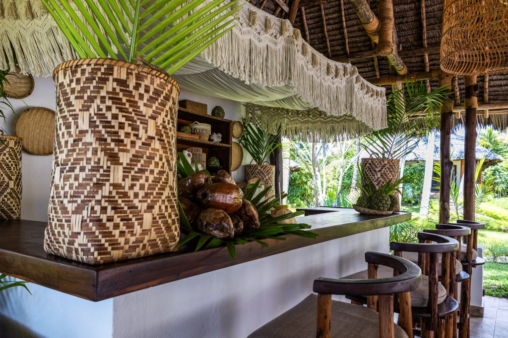Offene Pool Bar im The Palms Zanzibar mit Holztheke, Korbgefäßen, Palmblättern und Makramee-Dekorationen