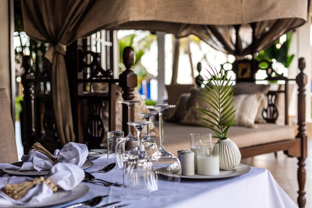 Gedeckter Tisch im Restaurant The Palms Zanzibar mit Weingläsern, Besteck, Servietten und Holzmöbeln