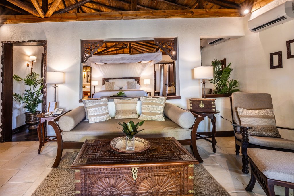 Zimmer der privaten Villa im The Palms Zanzibar mit Holzdecke, Couch, Couchtisch und Himmelbett