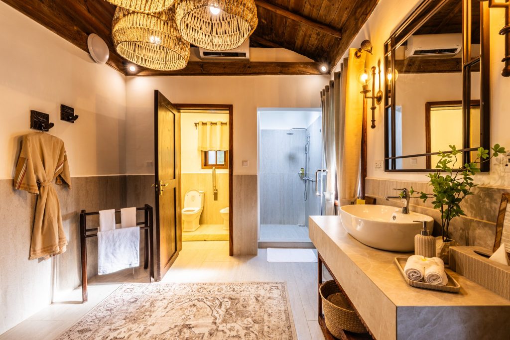 Badezimmer mit hellem Steinwaschtisch, großem Wandspiegel, Holzdecke und dekorativen Körben als Lampenschirme in Private.