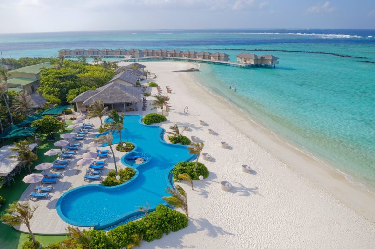 Resort You & Me Maldives mit zentralem Pool, blauen Liegestühlen, weißen Sonnenschirmen und Bungalows auf Stelzen