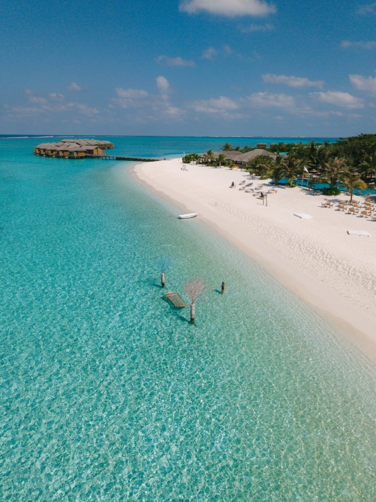 Strandresort You & Me Maldives mit weißem Sand, türkisfarbenem Wasser, Bungalows über Wasser und Holzsteg