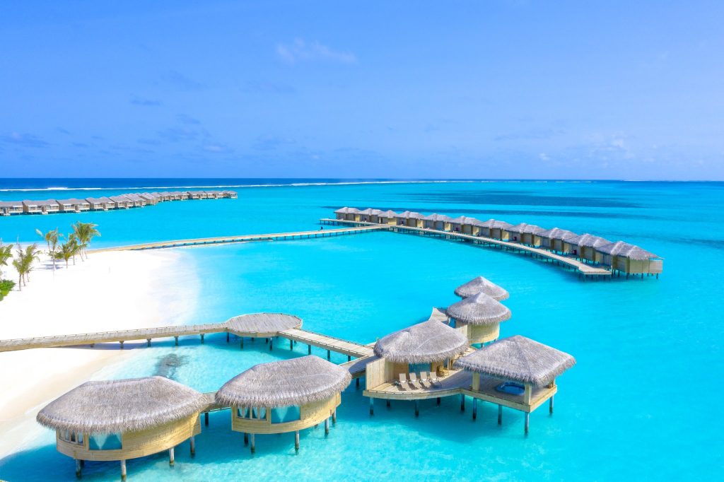 Auf Stelzen gebaute Wellness Spa Bungalows aus Holz und Stroh über türkisfarbenem Meer auf den