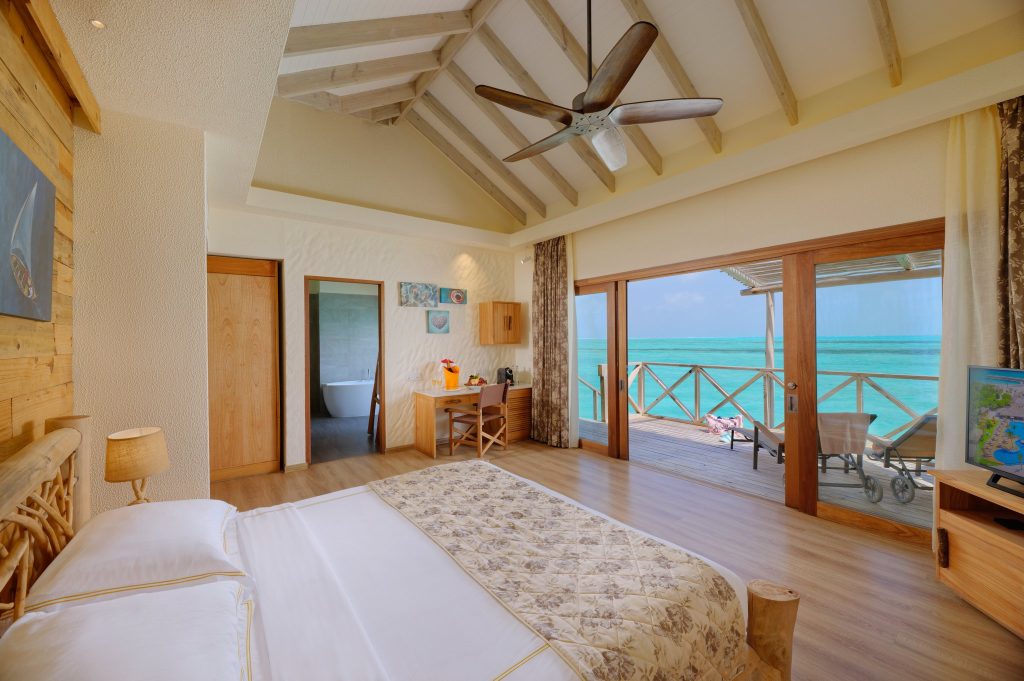 Hell eingerichtetes Zimmer Aqua Suite with Slide mit großem Bett, Holzwänden, Schreibtisch und Meerblick auf den