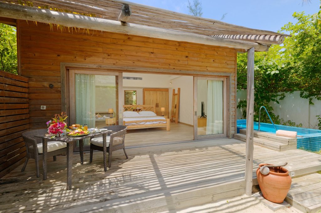 Terrasse der Beach Suite mit Rattan-Stühlen, Tisch, kleinem Pool und Schlafzimmer hinter Glasschiebetür auf den