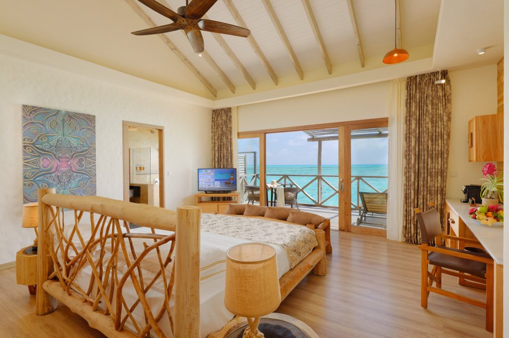 Geräumiges Zimmer der Lagoon Villa mit Holzbett, großem Fenster, Balkon und Blick auf den Ozean