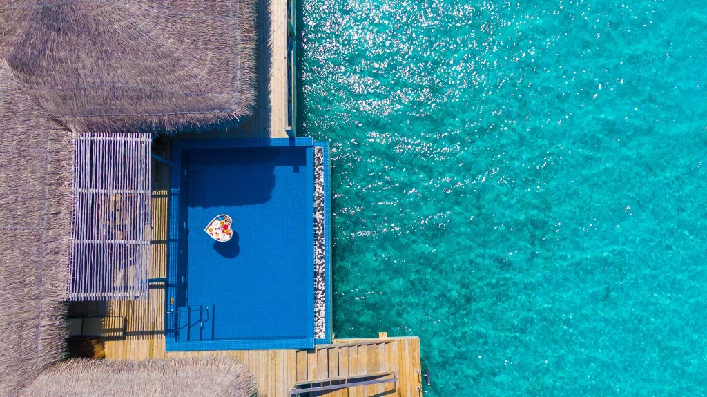 Luftaufnahme der You & Me Suite mit Holzterrasse, rechteckigem Pool und herzförmigem Tablett im Pool auf den
