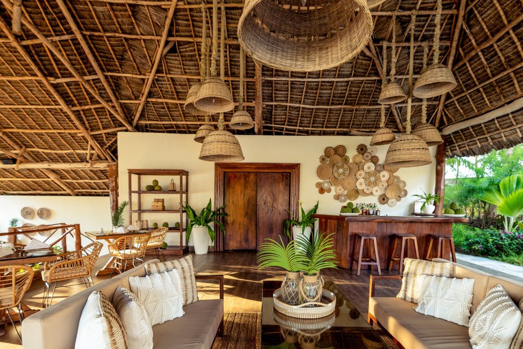Offene Bar im Zawadi Hotel mit Holz- und Korbmöbeln, hellen Kissen und hängenden Strohlampen